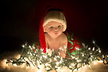 a baby in a santa hat and Christmas lights 