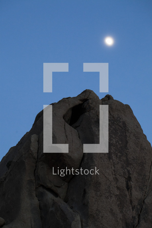 moon above a rock formation 