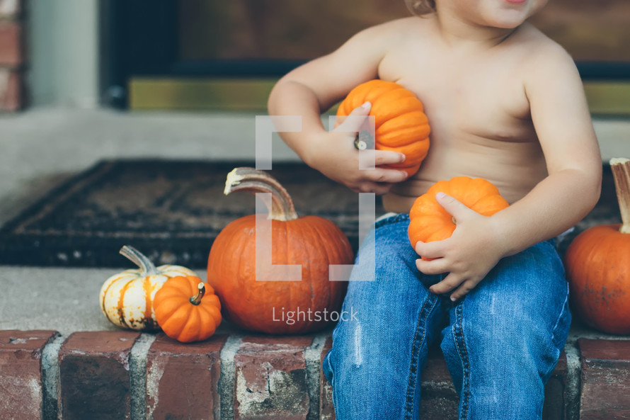 toddler holding pumpkins on steps 