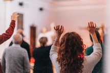 worshipers at a worship service with hands raised 