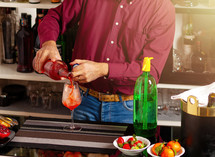 Man expertly preparing a colorful drink at a stylish bar setting