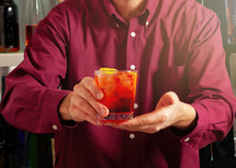 Close-up shot of a bartender offering a refreshing mixed drink