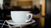 tea cup and saucer and earbuds on a table 