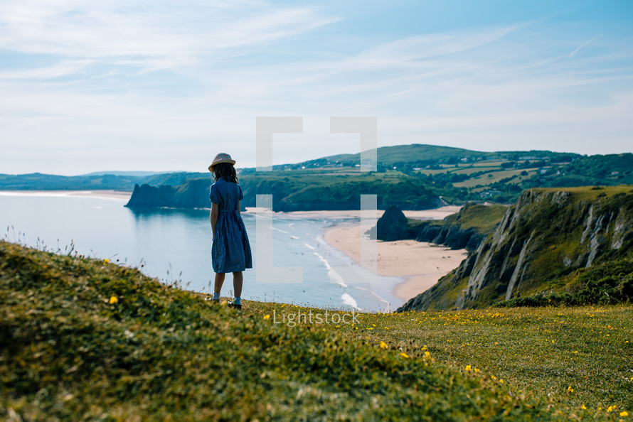 a girl standing on cliffs along a shore 