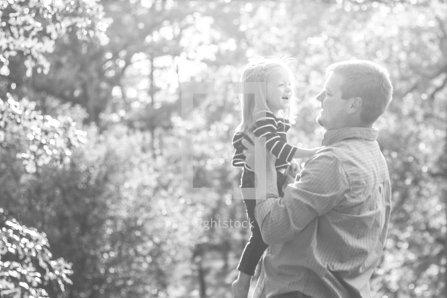 Father holding daughter outside.