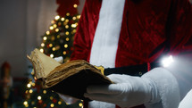 Santa Claus opening an old book in search of informations