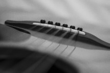 Close-up of a bridge and strings on an acoustical guitar.