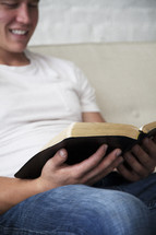 man reading a Bible smiling 