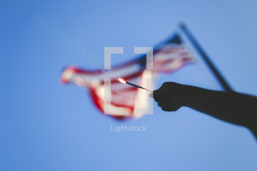 holding a sparkler in front of an American flag 