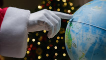 Santa tracing his road on the globe for Christmas