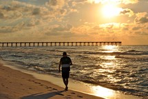 A beachcomber enjoys the solitude at daybreak near the fishing pier on Pensacola Beach, Florida. 