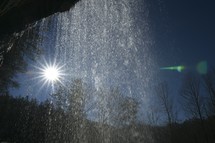 sunburst and waterfall over a cave 