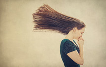 A woman in prayer as her hair is blown