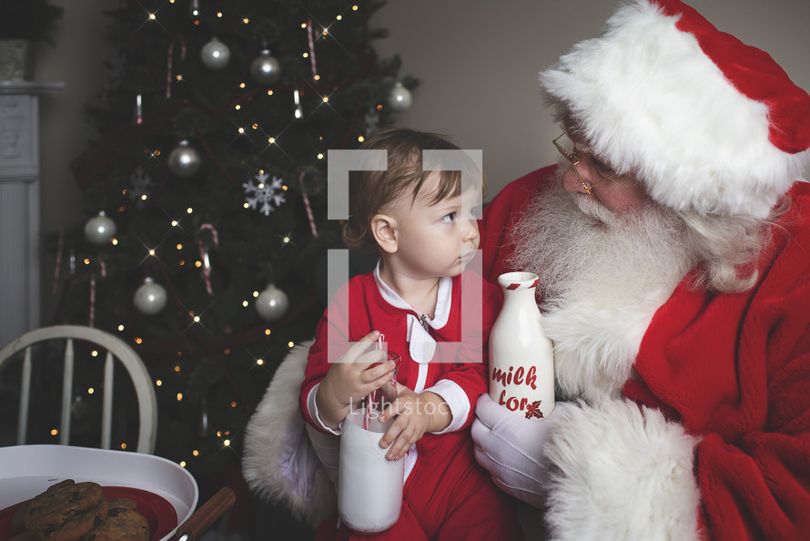 a toddler with cookies and milk on Santa's lap