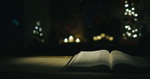 open Bible, Christmas gift, and bokeh candlelight 
