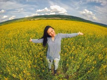 Portrait of young happy woman in rapeseed canola field. Springtime.