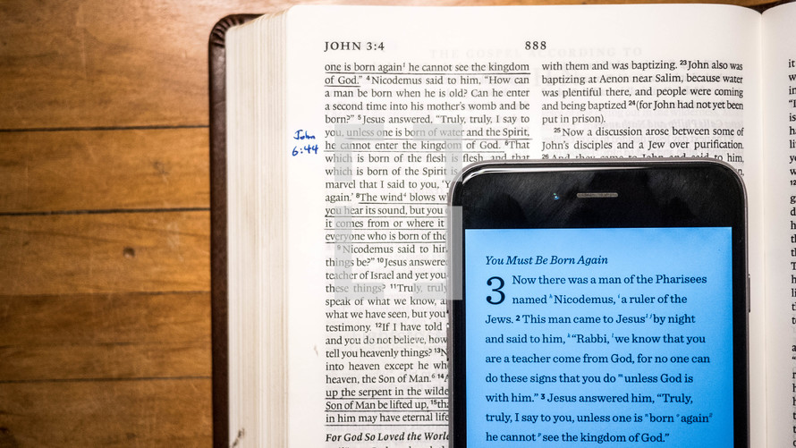 cellphone opened to a Bible app and an open Bible 
