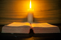 candle light and holy bible on wooden table in the night time.