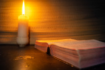 candle light and holy bible on wooden table in the night time.