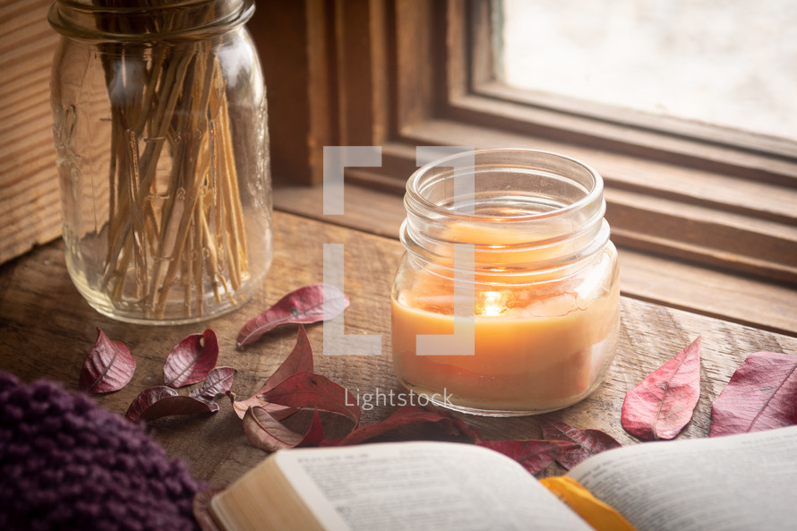 candle, fall leaves, and open Bible in a window 