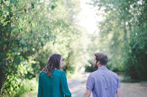 a couple walking hand in hand outdoors on a path 