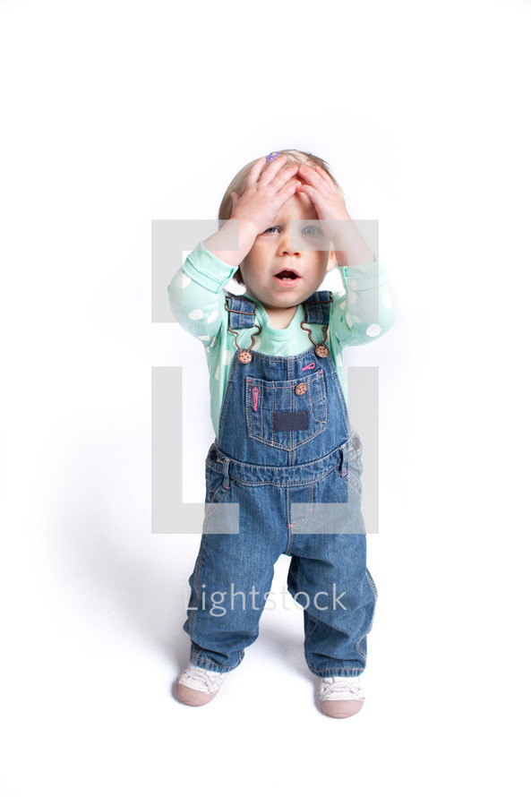toddler girl touching her forehead 