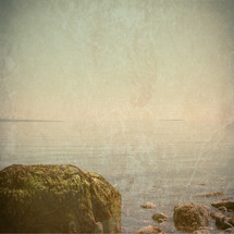 moss covered boulders on rocky ocean shore - vintage grunge for effect
