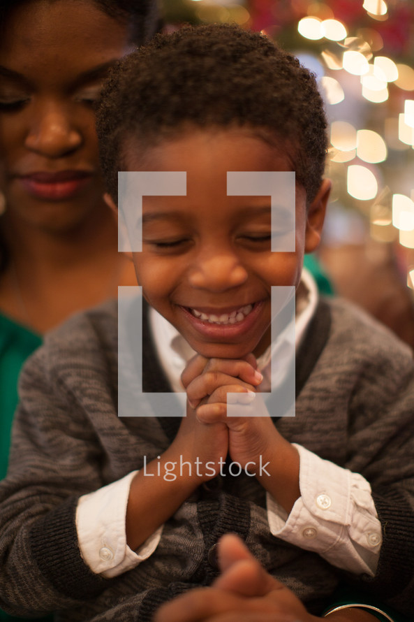 mother and son praying in front of a Christmas tree 