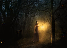 woman carrying a lantern in a dark forest 