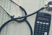 stethoscope, calculator, and financial book 
