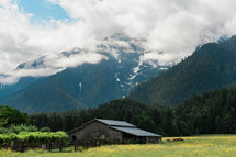 an old barn in a valley with mountains in the background 