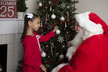 a child and Santa decorating a Christmas tree 