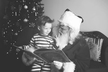 Santa and a boy reading a book together 