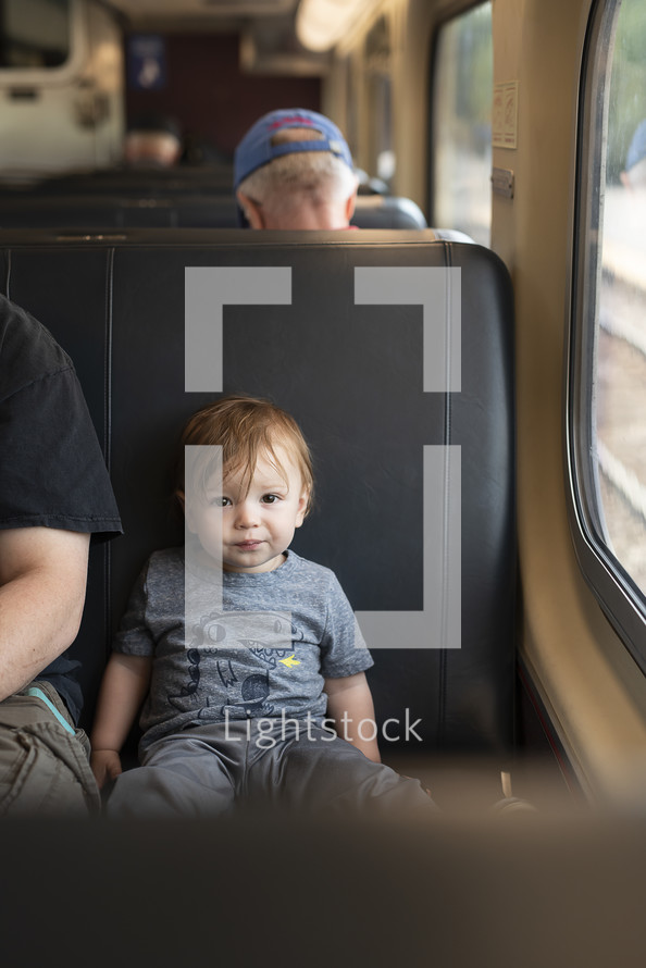 toddler boy in a train seat 