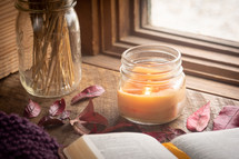 candle, fall leaves, and open Bible in a window 