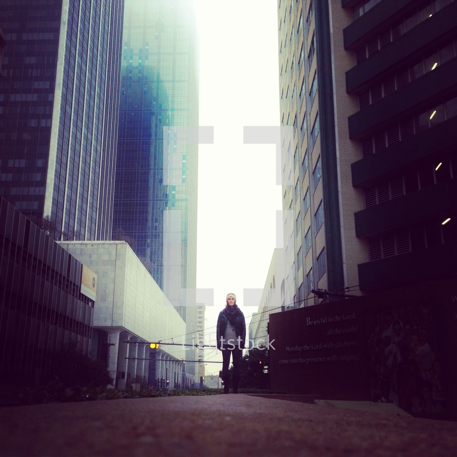 woman standing in an alley in a winter hat and scarf between two skyscrapers