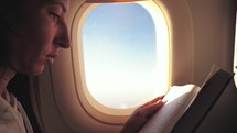 Woman reading book inside airplane. Happy traveler reading a book in an airplane.