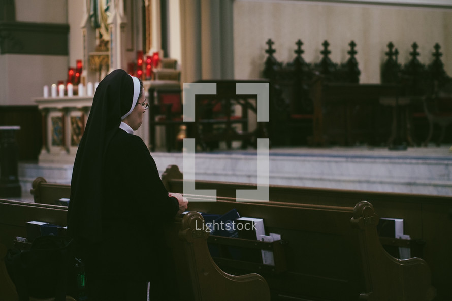 A roman Catholic nun praying the rosary in a church