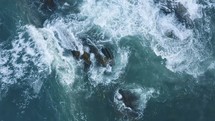 Aerial shot of waves crashing on rocks
