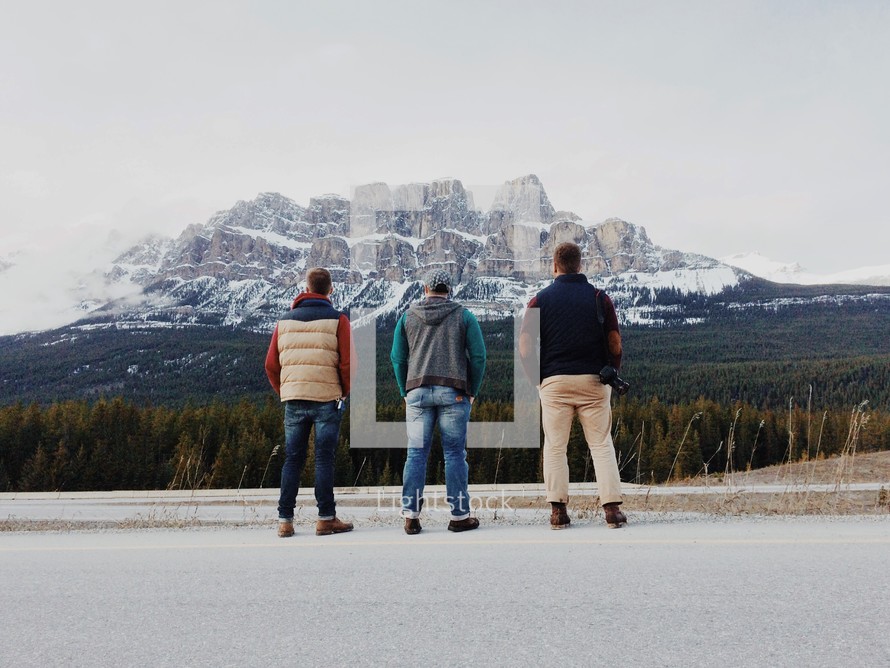 three men looking at a mountain 