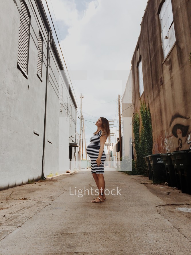 pregnant woman standing in an alley 