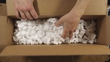 A man looking through a box with foam packing peanuts