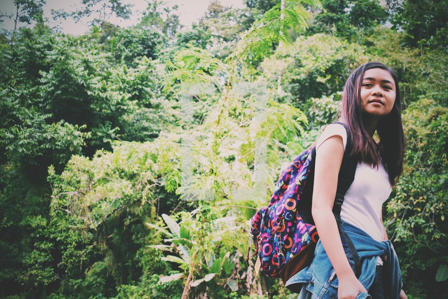 teen girl with a backpack in a jungle 