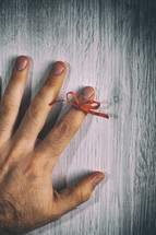 Red String Tied Around a Finger. Memory and Reminder Knot.