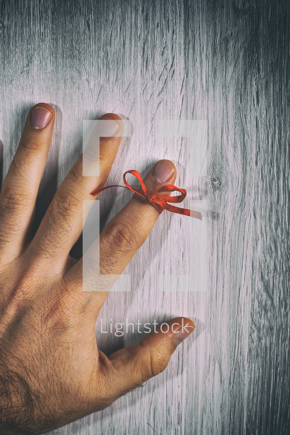 Red String Tied Around a Finger. Memory and Reminder Knot.