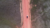 Overhead drone footage of a truck on a red, dirt road in Honduras