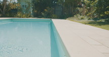 Tracking shot of a backyard swimming pool.