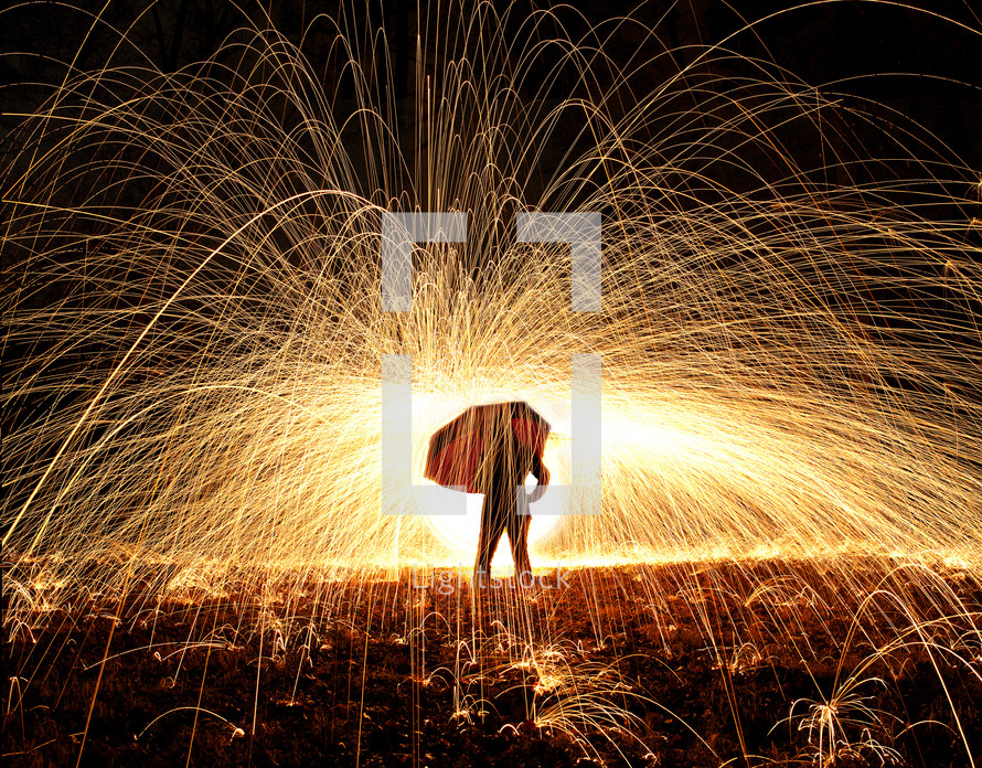 shower of sparks and a man standing under an umbrella 