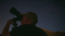 A man gazing at the stars through a small telescope