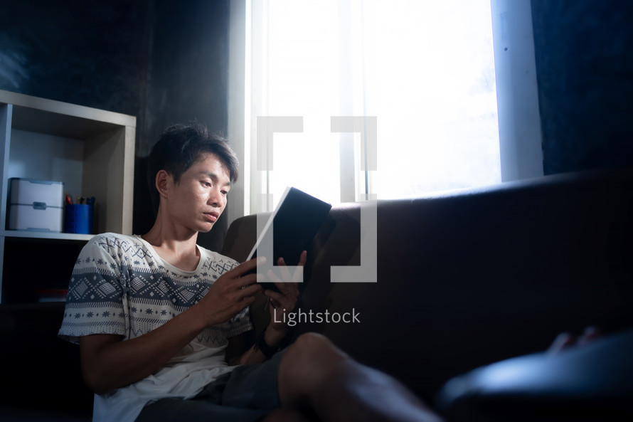 Asian man holding a Bible and reading